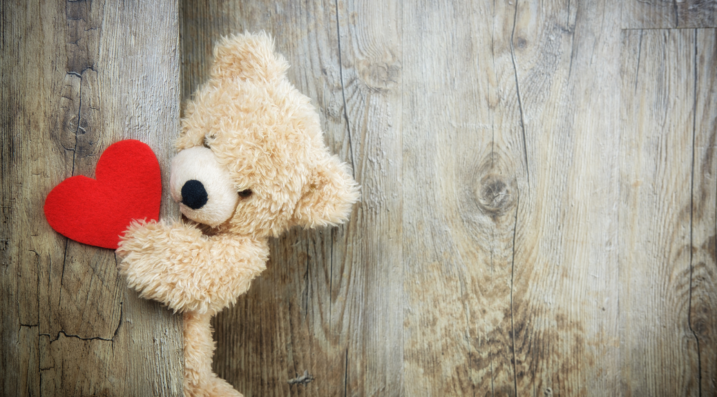 Teddybär hält ein Herz in der Hand